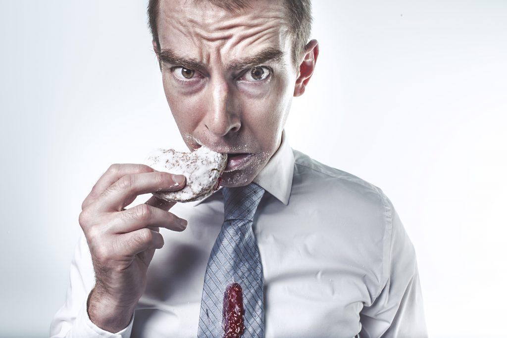 A man in necktie is hesitant to eat the crinkle cookies.