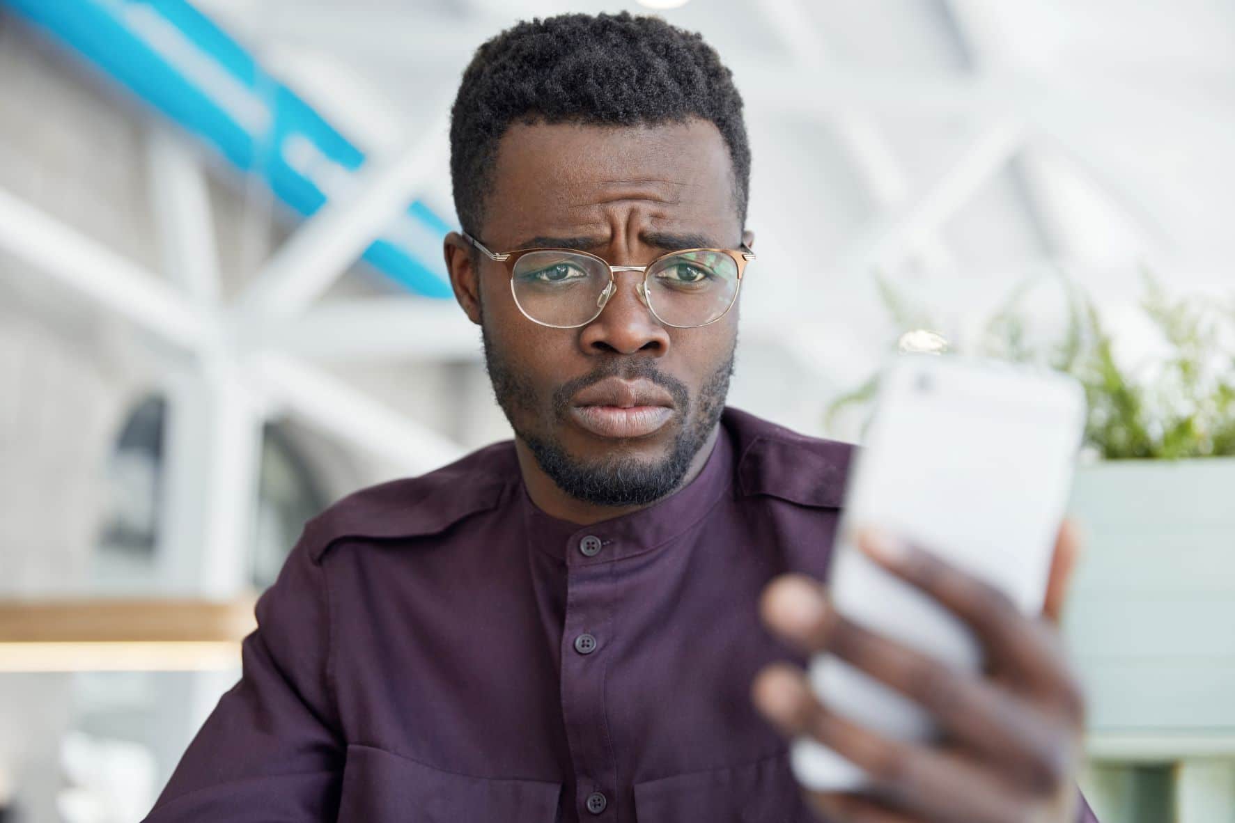 A black man looking worried at what he saw on his phone.