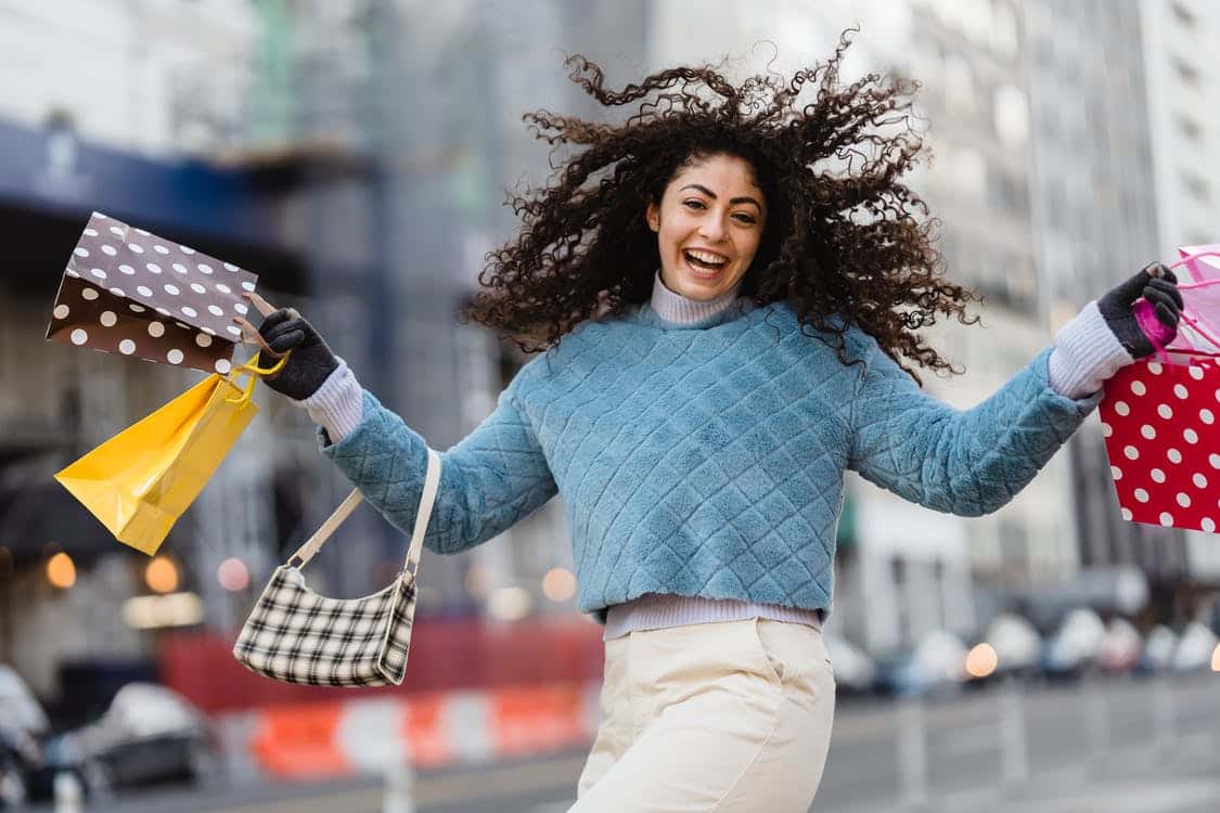 Excited Girl carrying shopping bags in the city.