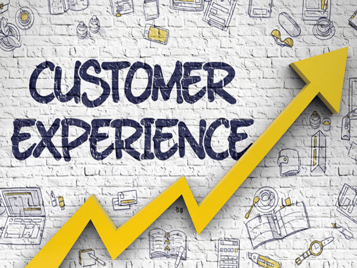 The word Customer Experience and a yellow rising arrow are written on a white wall.