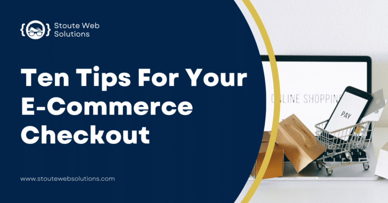 A miniature shopping cart with a phone, cards and paper bags sits before a laptop.